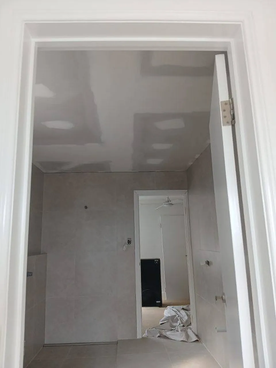Bathroom from the doorway before painting, ceiling patched and floor covered