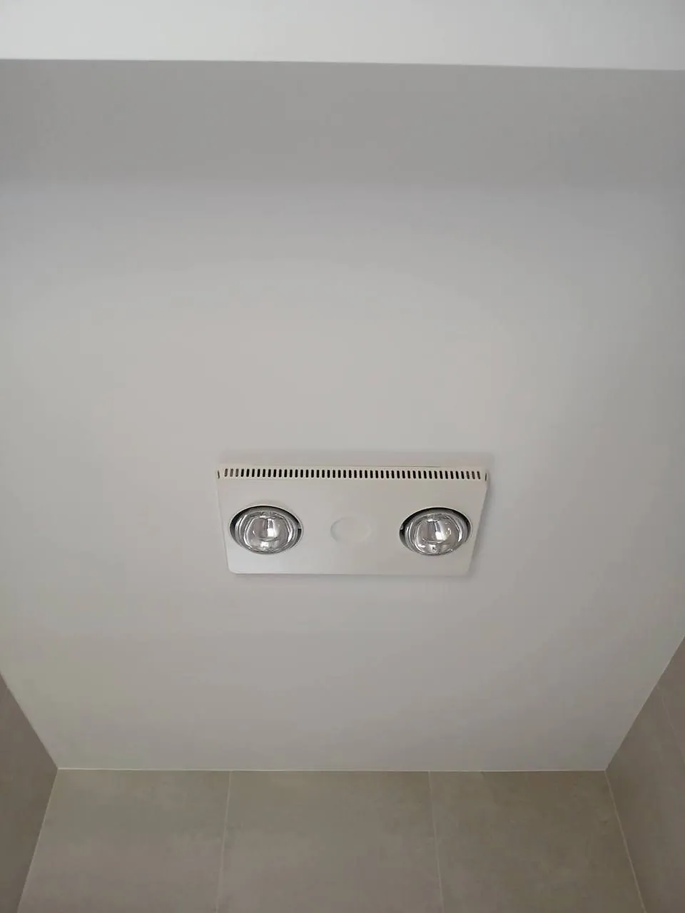 Freshly painted white bathroom ceiling around the heat lamp