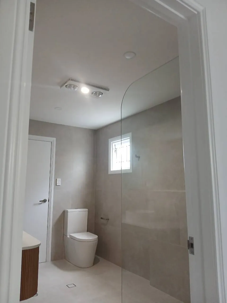 Bathroom from the doorway with glass screen and toilet fitted